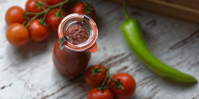 Ketchup | © SONNENTOR Auf dem Foto sieht man ein Glas mit selbstgemachtem Ketchup. Daneben sieht man frische Tomaten und einen grünen Paprika. | © SONNENTOR