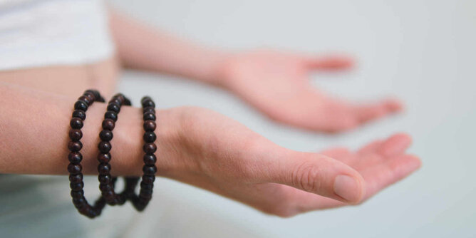 Achtsamkeitsübung | © SONNENTOR Auf dem Foto sieht man die Hände einer Frau mit den Handflächen nach oben gerichtet. Sie trägt drei Armbänder aus Holzkugeln. | © SONNENTOR