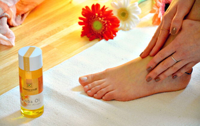 Ayurvedische Fußmassage | © SONNENTOR Auf dem Foto sieht man, wie sich jemand den Fuß mit Jojobaöl massiert. | © SONNENTOR