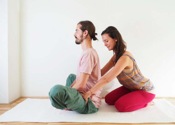 Schmetterling Yogaübung | © SONNENTOR Auf dem Foto ist ein Mann bei de Yogaübung Schmetterling zu sehen. Seine Übungspartnerin unterstützt ihn dabei. | © SONNENTOR